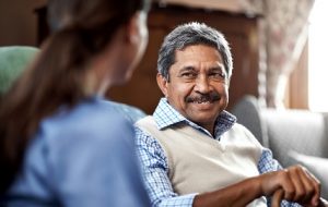 Carer taking care of elderly male resident who is smiling