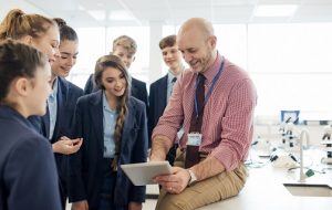 A male teacher talking to a group of students in a science room