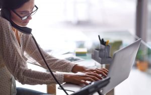 Busy Headteacher's Executive PAwoman multitasking on phone and typing into laptop